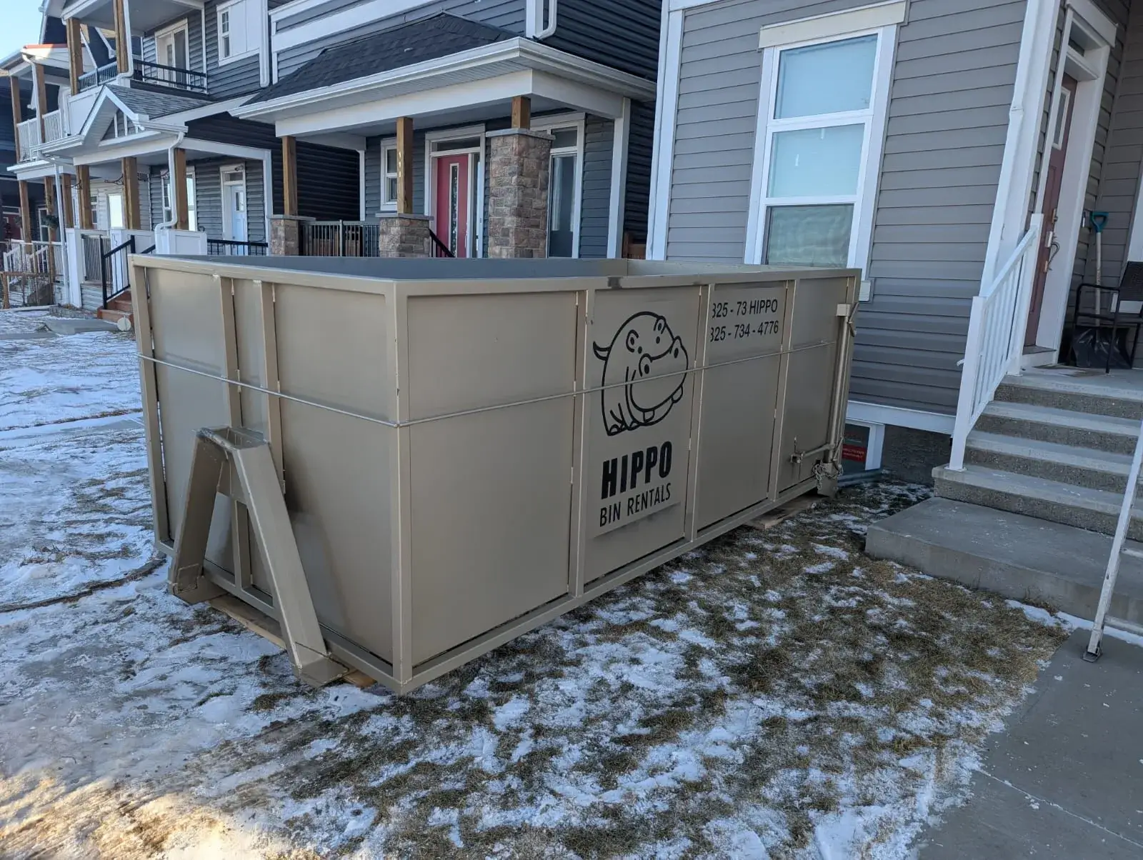 Calgary bin rental dumpster with hippo logo beside a residential walkway