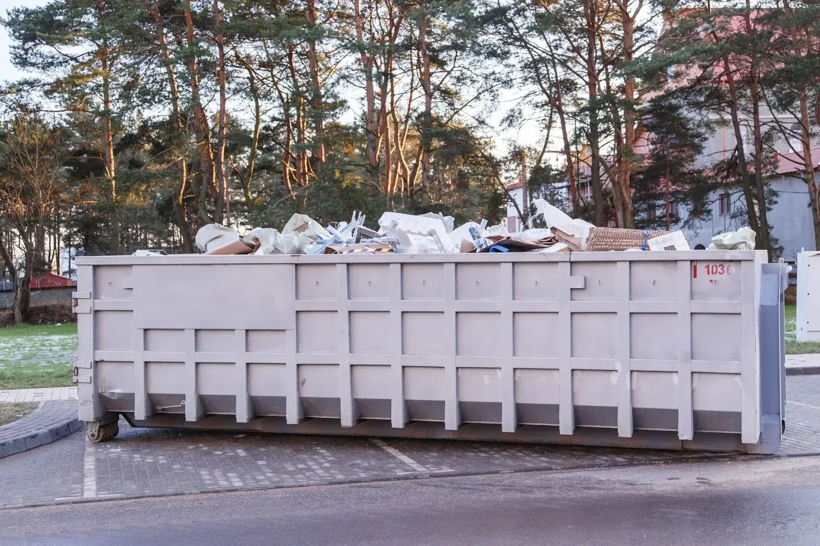 Roll off bins overflowing with discarded materials in a wooded area