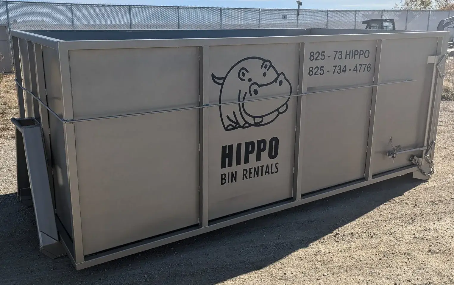 A large metal dumpster with a hippo logo and rental information displayed on it