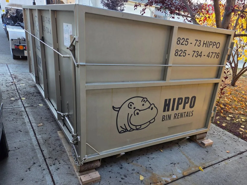 A large dumpster with a hippo logo sits on a driveway